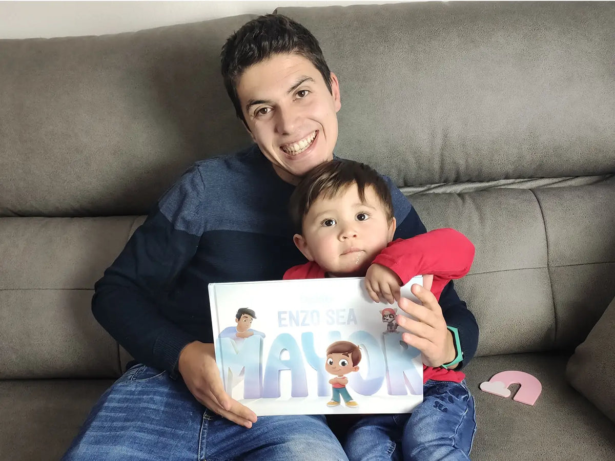 Hombre sosteniendo amorosamente a su pequeño hijo y a su perro leyendo un libro emocional sobre qué será su hijo cuando crezca.
