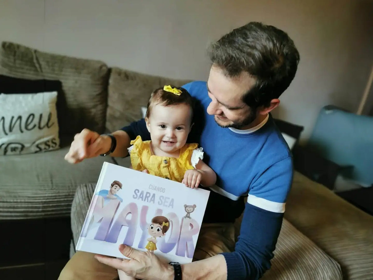 Niña sonriendo mientras su papá lee de un libro personalizado que recibieron por Navidad.