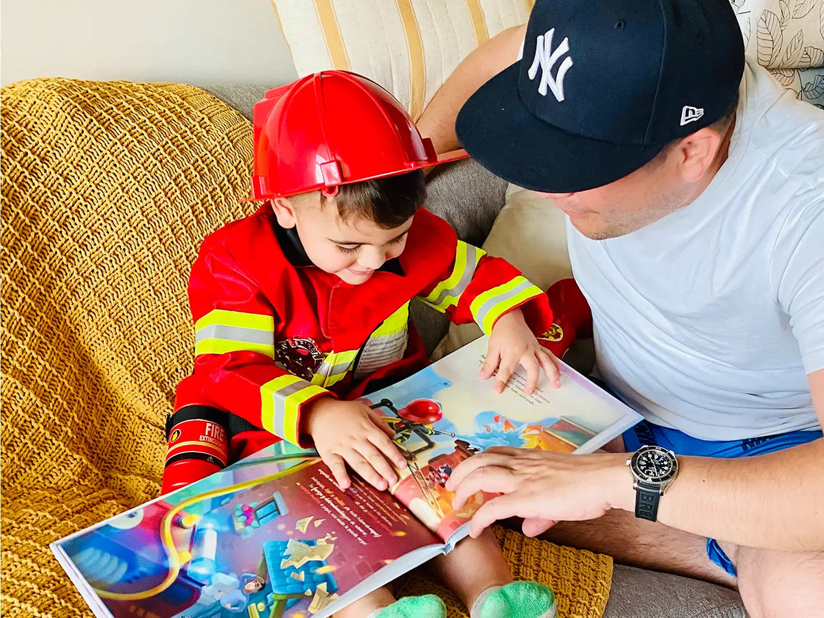 Niño vestido de bombero leyendo su libro DIY sobre él y su papá.